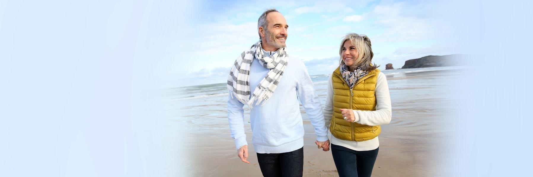 Older couple walking on beach l Cosmetic Dentistry Randwick, NSW